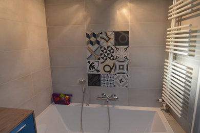 Cette image montre une salle d'eau de taille moyenne avec une baignoire encastrée, un carrelage beige et un sol gris.