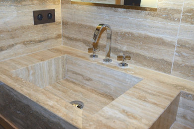 Cette image montre une salle de bain traditionnelle avec un carrelage marron, du carrelage en travertin, un mur marron et un plan vasque.