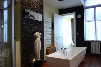 Idées déco pour une salle de bain contemporaine avec une baignoire indépendante, WC suspendus, un mur noir, un sol en bois brun, un plan vasque, un sol marron et un carrelage multicolore.
