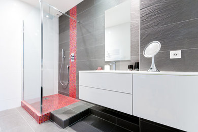 Idée de décoration pour une petite salle d'eau minimaliste avec un carrelage rose, du carrelage en ardoise, un mur gris, un sol en ardoise, un plan vasque, un plan de toilette en verre, un sol gris et une douche à l'italienne.