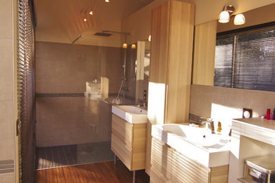 Cette image montre une très grande salle de bain principale design avec un plan vasque, un plan de toilette en surface solide, une baignoire encastrée, une douche à l'italienne, WC suspendus, un carrelage gris, des carreaux de céramique, un mur beige et parquet en bambou.
