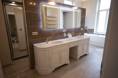 Design ideas for a large classic ensuite bathroom in Nancy with a hot tub, a built-in shower, brown tiles, ceramic tiles, beige walls, a console sink, an open shower, beaded cabinets, grey cabinets, light hardwood flooring, marble worktops, beige floors, grey worktops and a two-piece toilet.