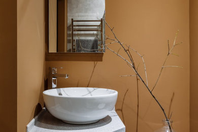 Cette image montre une petite salle d'eau vintage avec une douche d'angle, WC suspendus, un mur marron, une vasque, un plan de toilette en granite, un sol gris, une cabine de douche à porte coulissante, meuble simple vasque et meuble-lavabo suspendu.