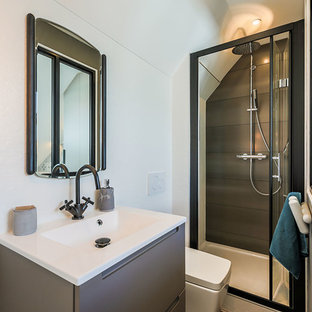 Aménagement d'une salle de bain contemporaine avec un placard à porte plane, des portes de placard grises, un WC suspendu, un mur blanc, un plan vasque et une cabine de douche à porte battante.