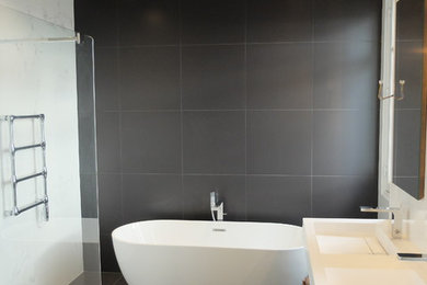 Cette image montre une salle de bain principale design en bois foncé de taille moyenne avec une baignoire posée, une douche à l'italienne, WC suspendus, un mur blanc, un sol en carrelage de céramique, un carrelage gris, un plan vasque, un sol gris, aucune cabine, un plan de toilette blanc, des carreaux de céramique et un plan de toilette en marbre.