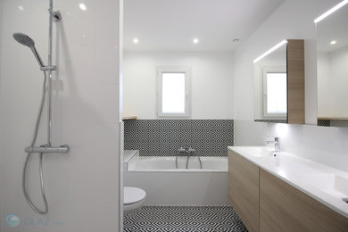 Exemple d'une douche en alcôve principale tendance en bois clair de taille moyenne avec un placard à porte affleurante, une baignoire posée, WC suspendus, un carrelage blanc, des carreaux de céramique, un mur blanc, carreaux de ciment au sol, un lavabo posé, un plan de toilette en surface solide, un sol noir, une cabine de douche à porte battante et un plan de toilette blanc.