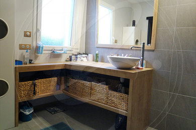 Cette image montre une salle de bain design de taille moyenne avec une douche à l'italienne, un carrelage gris, des carreaux de céramique, un mur gris, un sol en carrelage de céramique, un lavabo posé, un plan de toilette en bois et un sol gris.