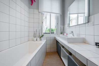 Aménagement d'une salle de bain classique avec une baignoire encastrée, un carrelage blanc, un lavabo posé, un plan de toilette en carrelage et un plan de toilette blanc.