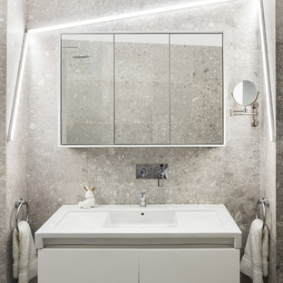 Exemple d'une petit salle de bain tendance avec un placard à porte plane, des portes de placard blanches, un lavabo intégré, un carrelage gris et un mur gris.