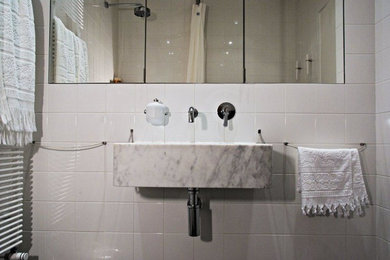 Cette photo montre une salle de bain principale tendance avec une douche à l'italienne, un carrelage blanc, des carreaux de béton, un mur blanc et un lavabo intégré.