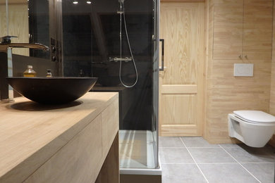 Design ideas for a small contemporary ensuite bathroom in Other with beaded cabinets, light wood cabinets, a submerged bath, a corner shower, a wall mounted toilet, grey tiles, ceramic tiles, brown walls, ceramic flooring, a console sink and wooden worktops.