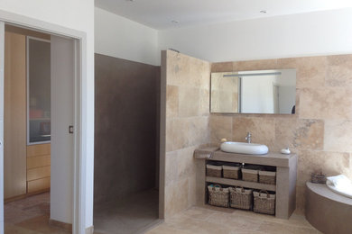 Réalisation d'une salle de bain principale design en bois clair de taille moyenne avec un placard à porte affleurante, une baignoire d'angle, une douche à l'italienne, WC suspendus, un carrelage beige, des dalles de pierre, un mur beige, un sol en carrelage de céramique, un lavabo posé et un plan de toilette en béton.