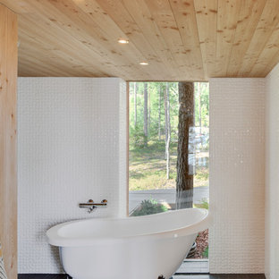 Cette photo montre une salle de bain principale scandinave de taille moyenne avec une baignoire sur pieds, un carrelage blanc, un mur blanc et un sol en ardoise.