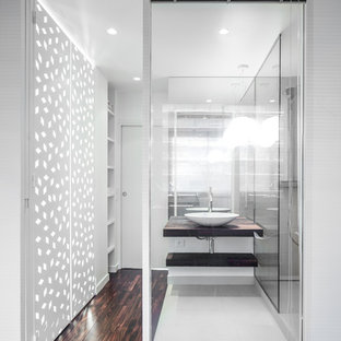 Réalisation d'une petit salle de bain design avec une vasque, un placard sans porte, des portes de placard en bois sombre, un mur blanc et un sol en bois foncé.