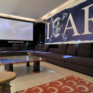 Réalisation d'une grand salle de cinéma design fermée avec un mur blanc, un sol en bois clair et un écran de projection.