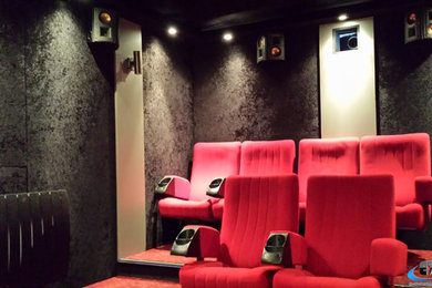 Foto de cine en casa cerrado moderno con paredes negras, moqueta, pantalla de proyección y suelo rojo