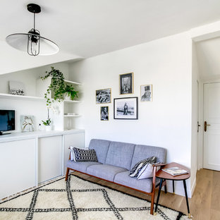 Idée de décoration pour une salle de séjour avec une bibliothèque ou un coin lecture nordique de taille moyenne avec un mur blanc, un sol en bois clair, aucune cheminée et un téléviseur indépendant.