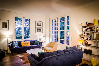 Ejemplo de sala de estar abierta actual de tamaño medio sin chimenea con paredes blancas, suelo de madera clara y suelo beige