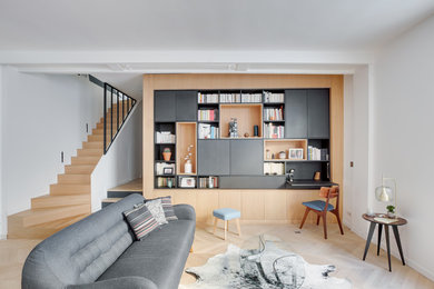 Exemple d'une grande salle de séjour tendance ouverte avec une bibliothèque ou un coin lecture, un mur blanc, parquet clair, aucune cheminée, un téléviseur dissimulé et un sol beige.