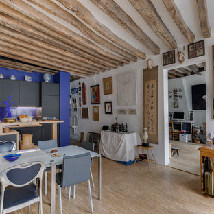 Réalisation d'une grand salle de séjour ethnique ouverte avec un mur blanc, un sol en bois clair, un sol beige, aucune cheminée et aucun téléviseur.