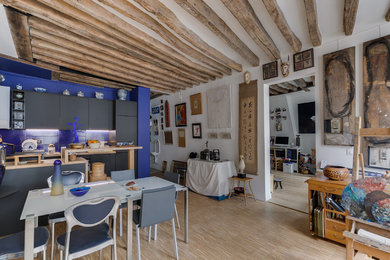 Diseño de sala de estar abierta tropical grande sin chimenea y televisor con paredes blancas, suelo de madera clara y suelo beige