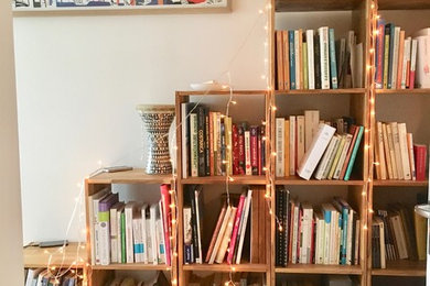 Exemple d'une petite salle de séjour éclectique ouverte avec une bibliothèque ou un coin lecture, un mur blanc, parquet clair, aucun téléviseur et un sol beige.