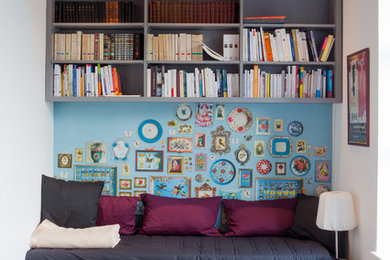Modelo de sala de estar con biblioteca cerrada bohemia pequeña sin chimenea y televisor con suelo de madera en tonos medios y paredes multicolor