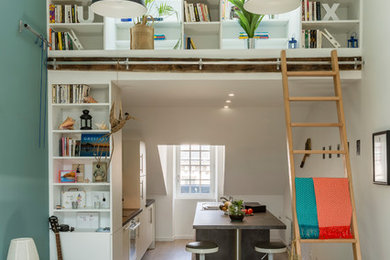 Diseño de sala de estar con biblioteca abierta contemporánea de tamaño medio sin chimenea y televisor con paredes verdes, suelo de madera clara y suelo beige