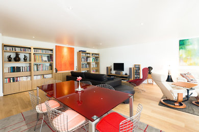 Cette image montre une grande salle de séjour design ouverte avec un mur blanc et parquet clair.