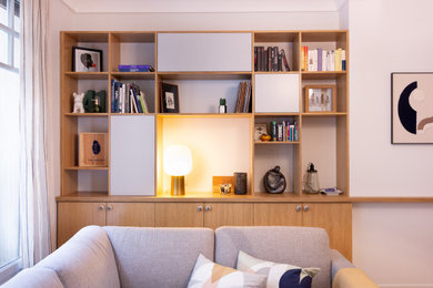 Cette photo montre une salle de séjour tendance de taille moyenne et ouverte avec une bibliothèque ou un coin lecture, un mur gris, parquet clair et un téléviseur fixé au mur.