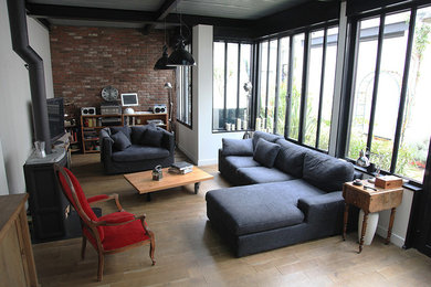 Aménagement d'une salle de séjour industrielle de taille moyenne et ouverte avec un mur blanc et un sol en bois brun.