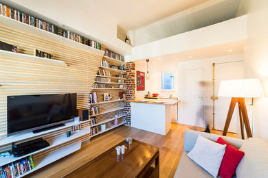 Réalisation d'une petite salle de séjour design ouverte avec une bibliothèque ou un coin lecture, un mur blanc, parquet clair, aucune cheminée, un téléviseur indépendant et un sol marron.