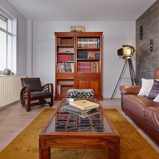 Cette image montre une salle de séjour avec une bibliothèque ou un coin lecture bohème de taille moyenne et fermée avec un mur gris, un sol en bois clair, aucune cheminée et un téléviseur indépendant.