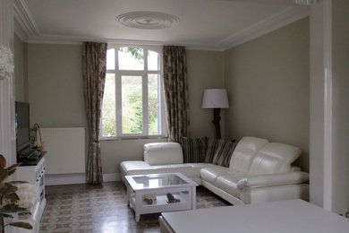 Cette image montre une grande salle de séjour traditionnelle fermée avec un mur beige, tomettes au sol, une cheminée standard et un manteau de cheminée en pierre.
