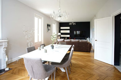 Aménagement d'une salle à manger classique avec un mur blanc, parquet clair, une cheminée standard et un sol marron.