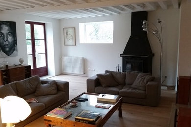 Large country open plan games room in Lyon with white walls, laminate floors, a wood burning stove, a metal fireplace surround, a freestanding tv and beige floors.