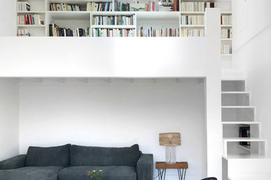 Modelo de sala de estar con biblioteca abierta contemporánea grande sin televisor con paredes blancas, suelo de madera pintada, suelo blanco y alfombra
