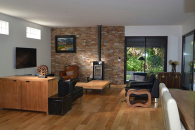 Foto de sala de estar abierta contemporánea de tamaño medio con paredes blancas, suelo de madera clara y televisor colgado en la pared