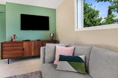 Foto de sala de estar con biblioteca abierta minimalista de tamaño medio sin chimenea con paredes beige, suelo de travertino, televisor colgado en la pared y suelo beige