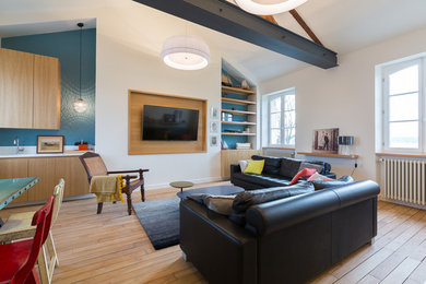 Cette image montre une grande salle de séjour bohème ouverte avec un mur bleu, parquet clair, aucune cheminée et un téléviseur fixé au mur.