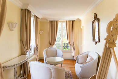 Cette image montre une salle de séjour traditionnelle de taille moyenne et ouverte avec un mur beige et parquet clair.