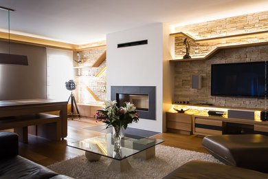 Réalisation d'une grande salle de séjour design avec un mur beige, un sol en bois brun, une cheminée standard, un manteau de cheminée en carrelage et un téléviseur fixé au mur.