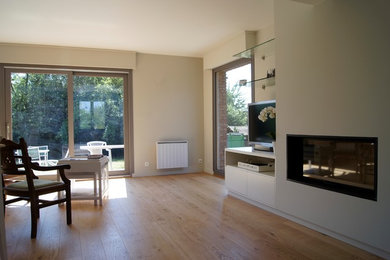 Ejemplo de sala de estar abierta contemporánea de tamaño medio con paredes blancas, suelo de madera clara, televisor independiente, chimenea lineal y suelo marrón