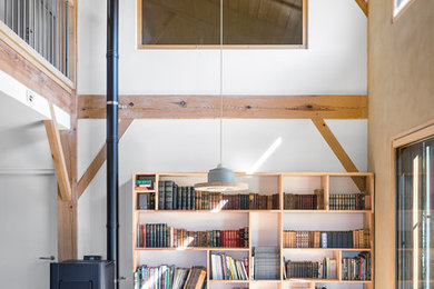 Cette image montre une salle de séjour rustique avec une bibliothèque ou un coin lecture, parquet clair et un poêle à bois.