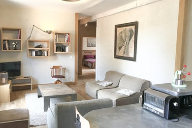 Foto de sala de estar con barra de bar abierta campestre grande sin chimenea con paredes beige, suelo de madera clara, televisor en una esquina y suelo beige