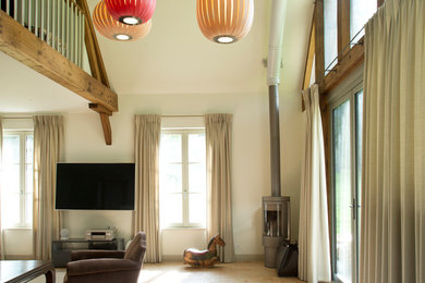 Inspiration pour une grande salle de séjour traditionnelle ouverte avec tomettes au sol, un poêle à bois, un téléviseur fixé au mur et un mur blanc.
