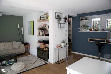 Idée de décoration pour une petite salle de séjour design ouverte avec un mur bleu, parquet clair, aucune cheminée, un téléviseur dissimulé et un sol marron.