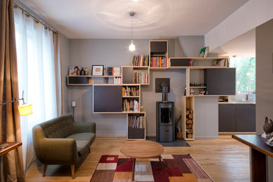 Imagen de sala de estar con biblioteca cerrada actual con paredes grises y suelo de madera clara