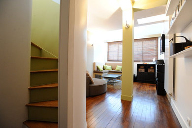 Aménagement d'une petite salle de séjour éclectique avec un mur vert et un sol en bois brun.