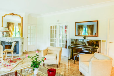 Exemple d'une salle de séjour chic de taille moyenne et ouverte avec un mur beige, un sol en marbre, une cheminée standard, un manteau de cheminée en pierre, un téléviseur dissimulé et un sol marron.